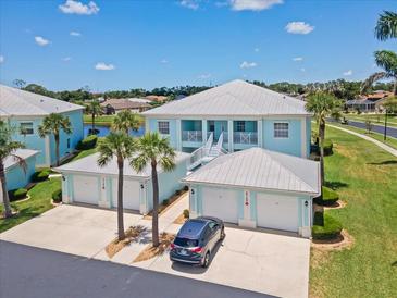 Beautiful light blue two-story home with multiple garages, a metal roof, and a well-manicured lawn at 5739 Sabal Trace Dr # 102, North Port, FL 34287