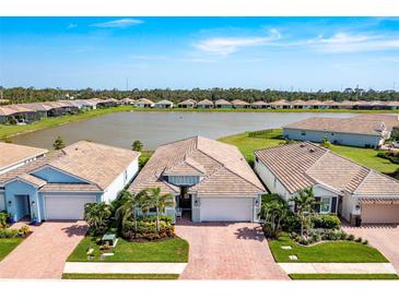 Stunning aerial view of the beautiful community, highlighting the lake and manicured landscaping at 629 Ibiza Loop, Venice, FL 34292