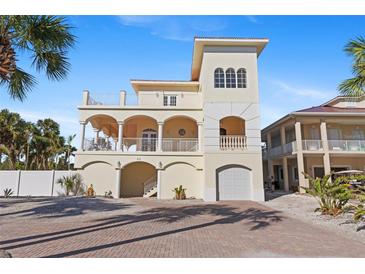 Beautiful three-story home with white pillars, balconies, and a brick driveway at 63 Palm Dr, Placida, FL 33946