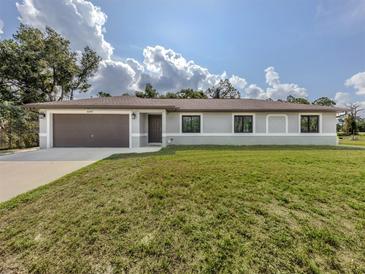 Charming single-story home with a lush front lawn, a two-car garage, and a welcoming entrance at 6497 Honeycomb Cir, North Port, FL 34291