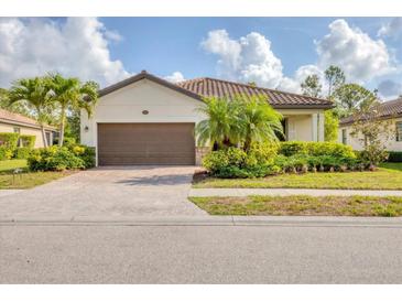 Charming single-story home with a well-manicured lawn, mature landscaping, and a brown tile roof at 12370 Canavese Ln, Venice, FL 34293