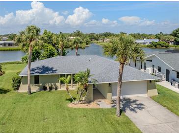 Beautiful single-story home with a two-car garage and lush green lawn with mature palm trees at 1240 Lucaya Ave, Venice, FL 34285