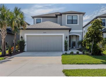 Two-story home featuring a well manicured lawn, a two-car garage, and a gray color scheme at 15364 Isla Palma Ln, Nokomis, FL 34275