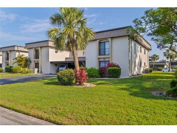 Well-maintained condo building with lush landscaping and covered parking on a sunny day at 1728 S Lakeside Ct # 1720B, Venice, FL 34293