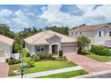 Charming single-story home featuring a clay tile roof, brick paver driveway, and well-manicured landscaping at 2034 Mesic Hammock Way, Venice, FL 34292