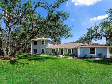 Charming two-story home with a sprawling lawn and mature trees offering curb appeal at 27215 Crosby Rd, Myakka City, FL 34251