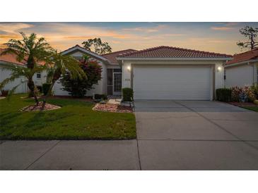 Charming single-story home with a well-manicured lawn, beautiful flowers, and a two-car garage at 4378 Summertree Rd, Venice, FL 34293