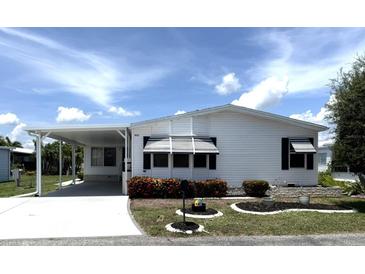 Charming single-story home with white siding, carport, well-manicured landscaping, and vibrant flowerbeds at 453 Sharks Pt, North Port, FL 34287