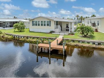 Waterfront home featuring a private dock, manicured lawn, and covered outdoor area perfect for grilling at 700 Blackburn Blvd, North Port, FL 34287