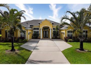 Inviting single-story home with a sunny yellow facade, lush palm trees, and an expansive driveway at 8209 Snowy Egret Pl, Bradenton, FL 34202