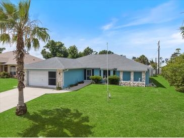 Charming single-story home with blue siding, stone accents, well-manicured lawn, and a palm tree in the front yard at 9277 Saint Catherine Ave, Englewood, FL 34224