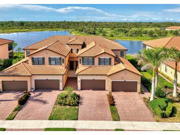 Beautiful townhome exterior featuring a tile roof, paver driveway and lush landscaping with waterfront view at 10789 Tarflower Dr # 202, Venice, FL 34293