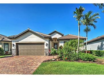 Charming single-story home boasts a brick driveway, two-car garage, and lush tropical landscaping at 13016 Rinella St, Venice, FL 34293