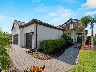 Charming home exterior with a three-car garage, tiled roof, and a beautifully landscaped walkway at 13056 Steinhatchee Loop, Venice, FL 34293