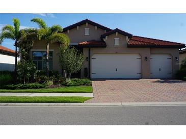 Charming home featuring a red tile roof, two-car garage, well-maintained landscaping and a brick driveway at 136 Positano Trl, Nokomis, FL 34275