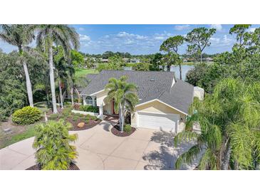 Charming yellow house featuring a well-manicured lawn, palm trees, and a circular driveway at 249 Hallcrest Ter, Port Charlotte, FL 33954