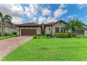 Charming home with a well-manicured lawn, lush landscaping, and a brown two-car garage at 4740 Royal Dornoch Cir, Bradenton, FL 34211