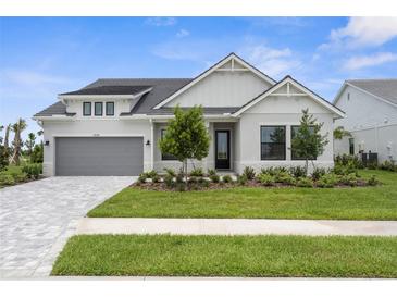 Charming two-story home featuring a gray garage door, stone accents, and well-manicured landscaping at 18136 Foxtail Loop, Venice, FL 34293