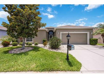 Charming home featuring a well-manicured lawn, mature trees, and a two-car garage on a sunny day at 24536 Buckingham Way, Port Charlotte, FL 33980