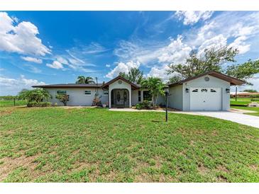 Charming single-story home with a well-manicured lawn, screened entryway and detached garage at 3376 Peace River Dr, Punta Gorda, FL 33983