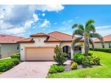 Charming single-story home featuring a red tile roof, paver driveway, and lush tropical landscaping at 10061 Cozy Grove Dr, Venice, FL 34293