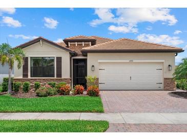 Beautiful single-story home with a tile roof, manicured lawn, and brick driveway at 11970 Lovegrass St, Venice, FL 34293
