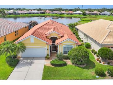 Beautiful home features a tile roof, well maintained landscaping, and a serene lake view at 1620 San Silvestro Dr, Venice, FL 34285