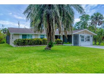 Charming single-story home featuring a lush green lawn and a mature palm tree in the front yard at 386 Nightingale Rd, Venice, FL 34293