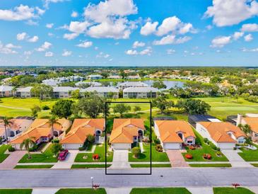 An aerial view of a single-Gathering home with a red tile roof and lush landscaping in a golf community at 4114 Murfield E Dr, Bradenton, FL 34203