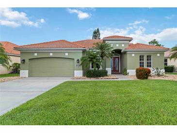Charming green home featuring a well-manicured lawn, desert landscaping, and a red tile roof at 6619 Pinefeather Ct, Bradenton, FL 34203