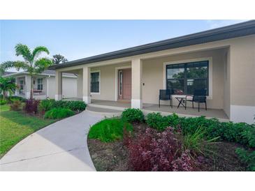 Inviting front porch of a charming single-story home with well-manicured landscaping and seating area at 7257 Maguire Ln, Englewood, FL 34224