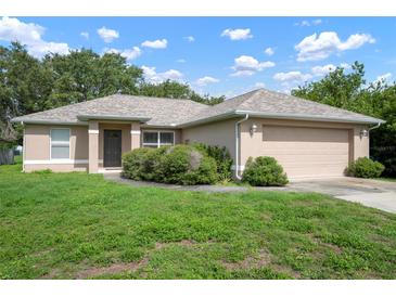 Welcoming single-story home with lush greenery and an attached two-car garage exudes charm and curb appeal at 2397 Morton Rd, North Port, FL 34291
