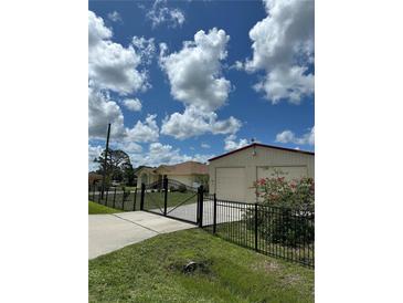Charming home featuring an automatic driveway gate, an oversized garage, and lush, green lawn at 102 Bayamo Dr, North Port, FL 34287
