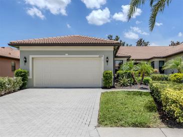 Charming single-story home featuring a tile roof, brick driveway, and well-manicured landscaping at 11192 Campazzo Dr, Venice, FL 34292