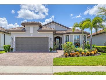 Beautiful single-story home with lush landscaping, a brick driveway, and a two-car garage at 13092 Rinella St, Venice, FL 34293