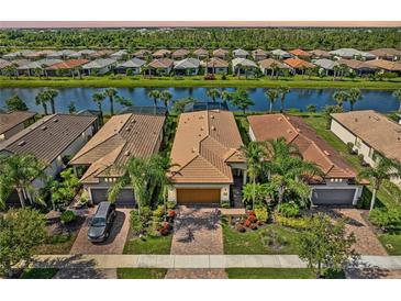 Beautiful aerial view of homes with tile roofs, manicured landscaping, and a serene lake in the community at 13841 Campoleone St, Venice, FL 34293