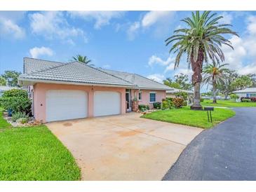 Charming single-story home featuring a well-manicured lawn, tiled roof, palm trees, and a two-car garage at 16 Oakwood N Dr # 16, Englewood, FL 34223