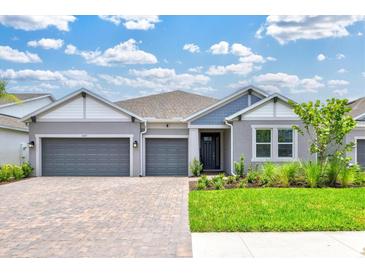 Charming single-story home featuring a three-car garage, lush landscaping, and a welcoming entrance at 1607 Laurel Brook Ln, Port Charlotte, FL 33953