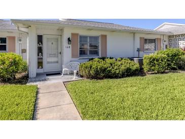 Charming single-story home featuring a well-maintained lawn, walkway and quaint front door at 168 The Corso # 168, Venice, FL 34285
