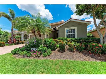 Charming home featuring lush landscaping, including palm trees, colorful flowers, and manicured shrubs at 2944 Oriole Dr, Sarasota, FL 34243