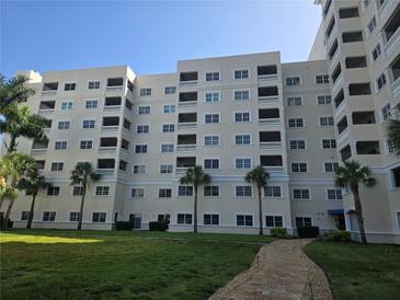 Multi-story condo complex with multiple units, balconies, and palm trees, set in a grassy lawn at 3730 Cadbury Cir # 703, Venice, FL 34293