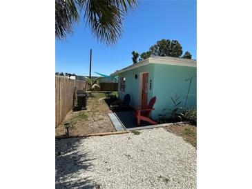 Charming exterior view featuring a teal home with coral colored door and Adirondack chairs at 700 Forest St, Nokomis, FL 34275