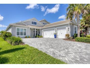 Stunning single-story home featuring a meticulously maintained lawn, paver driveway, and three-car garage at 8245 Grande Shores Dr, Sarasota, FL 34240