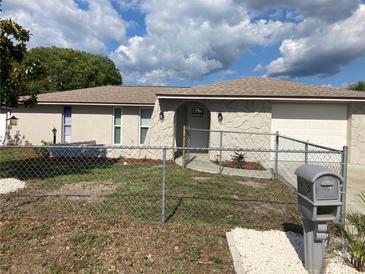 Charming single-story home featuring a decorative stone facade, fenced yard, and well-maintained landscaping at 9110 Lunar Ln, Port Richey, FL 34668