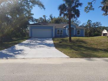 Charming single-story home featuring a wide driveway, manicured lawn, and a blue exterior at 16029 Arcaro Ave, Port Charlotte, FL 33954