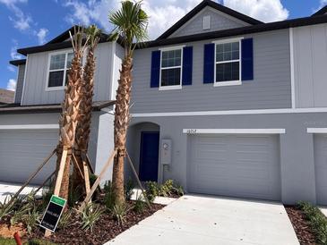 Two story house with gray siding, blue shutters, and palm trees at 10712 Ironwood Tree Way, San Antonio, FL 33576