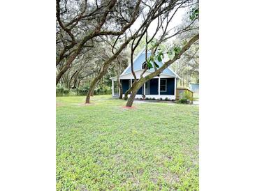 Charming blue house with a large front yard and mature trees at 34392 Broken Stone St, Webster, FL 33597