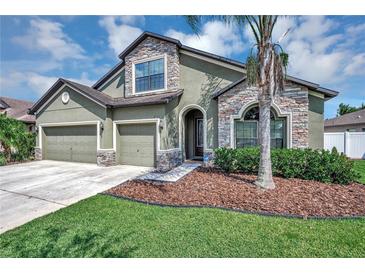 Two-story house with three-car garage, stone accents and palm trees at 6722 Wild Elm Ct, Wesley Chapel, FL 33545