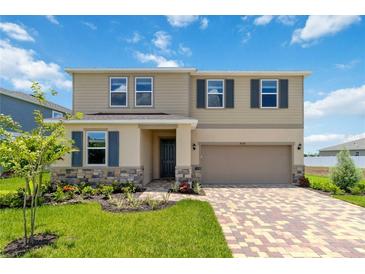 Two-story house with a neutral color scheme, landscaping, and a brick paver driveway at 9034 Sandy Bluffs Cir, Parrish, FL 34219