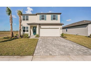 Two-story house with light beige siding, teal accents, and a paver driveway at 101 Runaway Field Ave, Nokomis, FL 34275